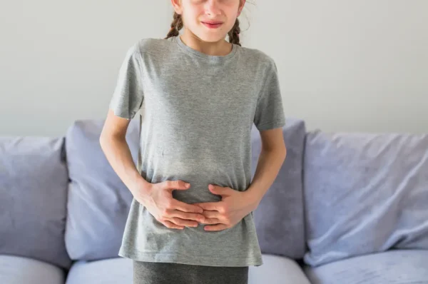 Child holding their stomach, which can be a sign of abdominal discomfort linked to constipation in children