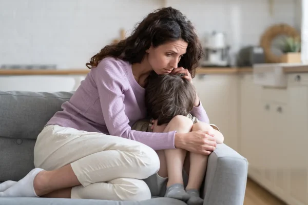 Small crying boy receiving love, protection and support from loving mom